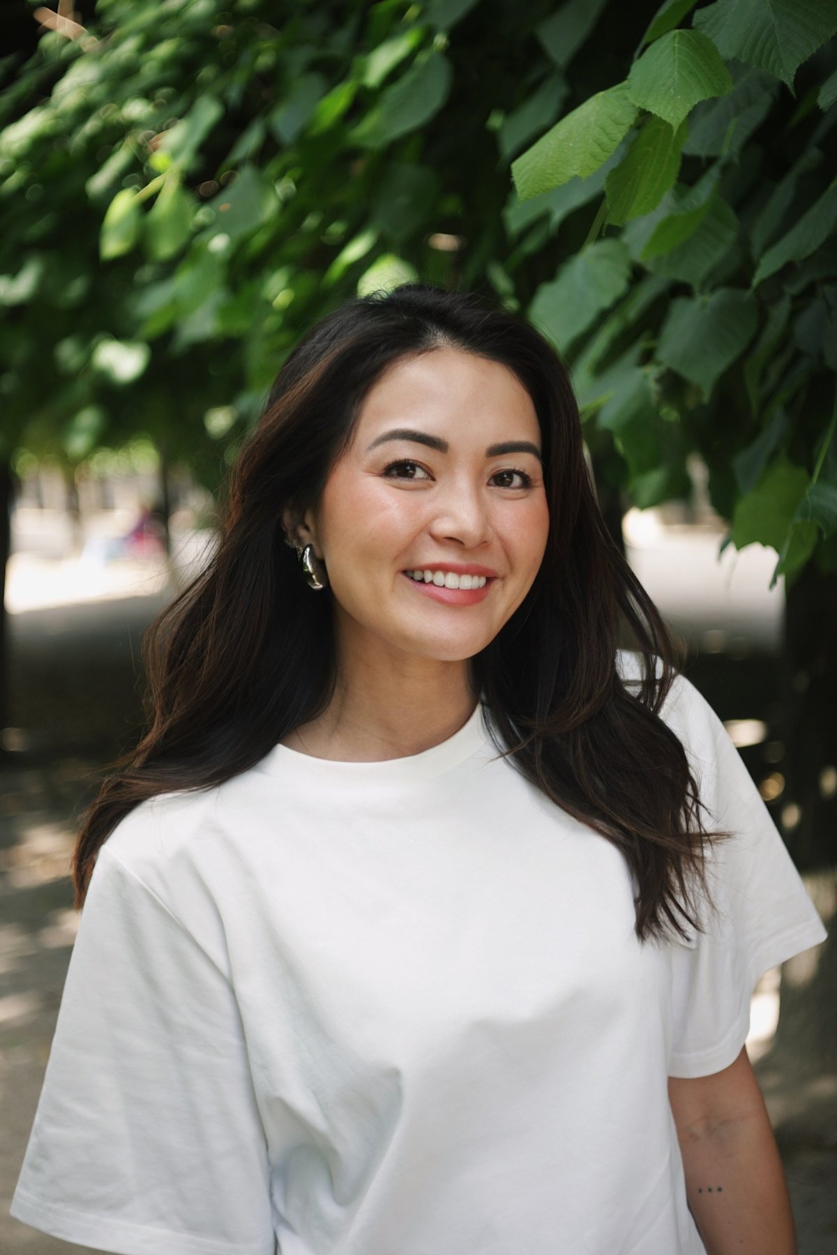 Christine Cameron, smiling, under a canopy of green leaves